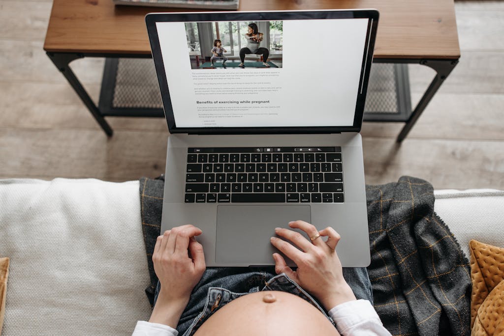 Pregnant woman uses laptop to read about exercising benefits during pregnancy.